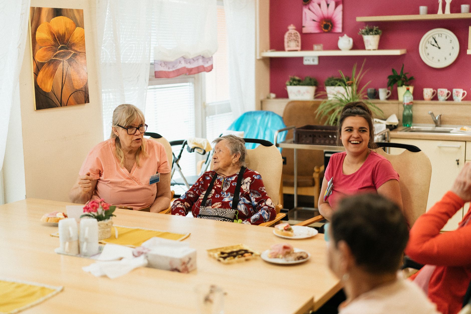 Seniors gathered around a table in a nursing home common area